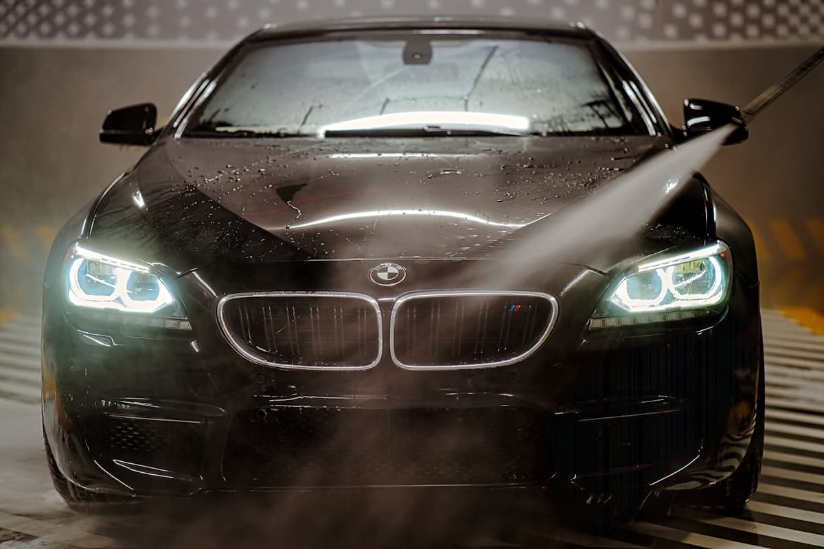 Black car hood with water spray during wash